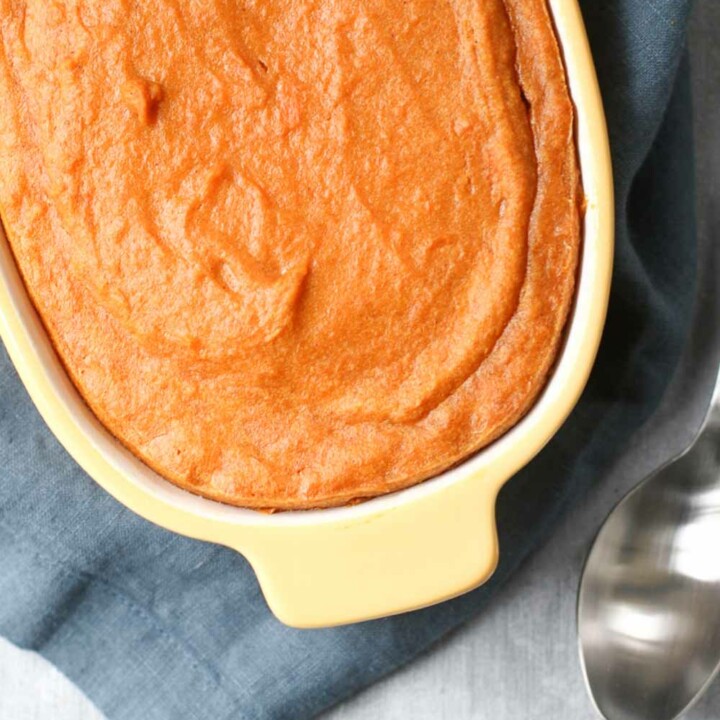Baked Sweet Potato Pudding in a yellow baking dish with a spoon