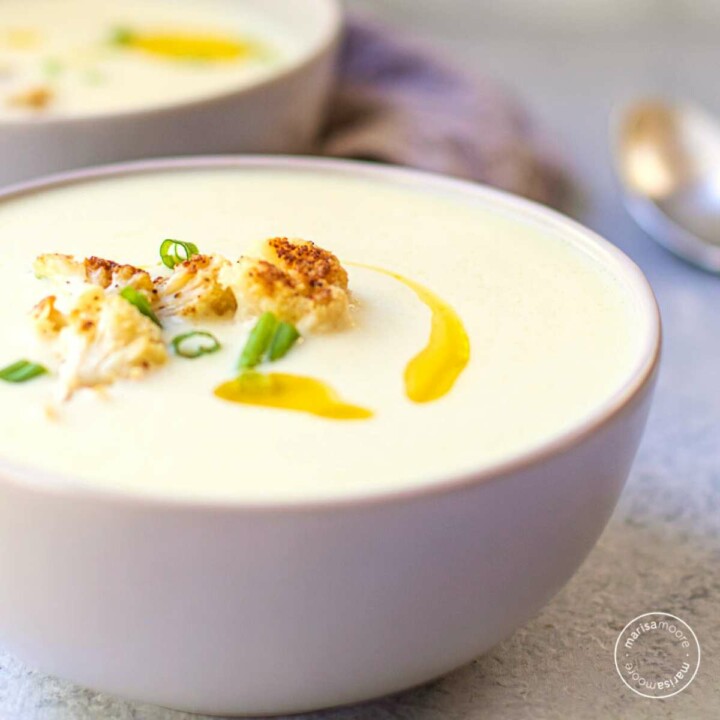Cauliflower soup in two gray bowls with spoons on the side