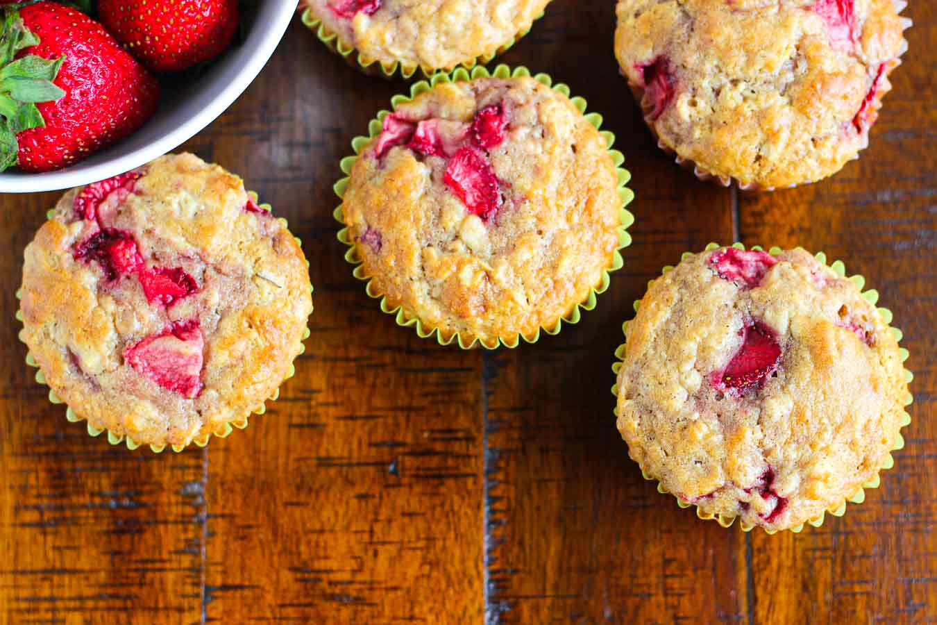 Strawberry muffins with a bowl of whole strawberries