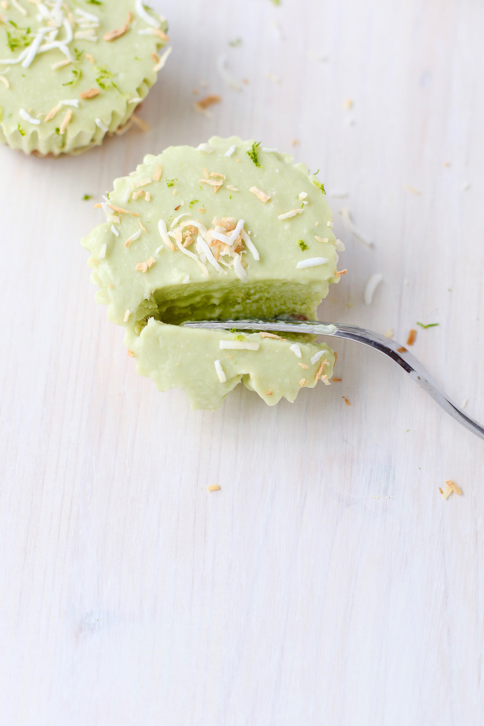 Coconut Avocado Lime Tartlets with a fork through one to show the inside.