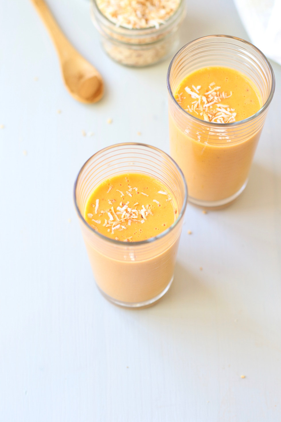Carrot Pineapple Smoothie in two glasses with Coconut sprinkles on top