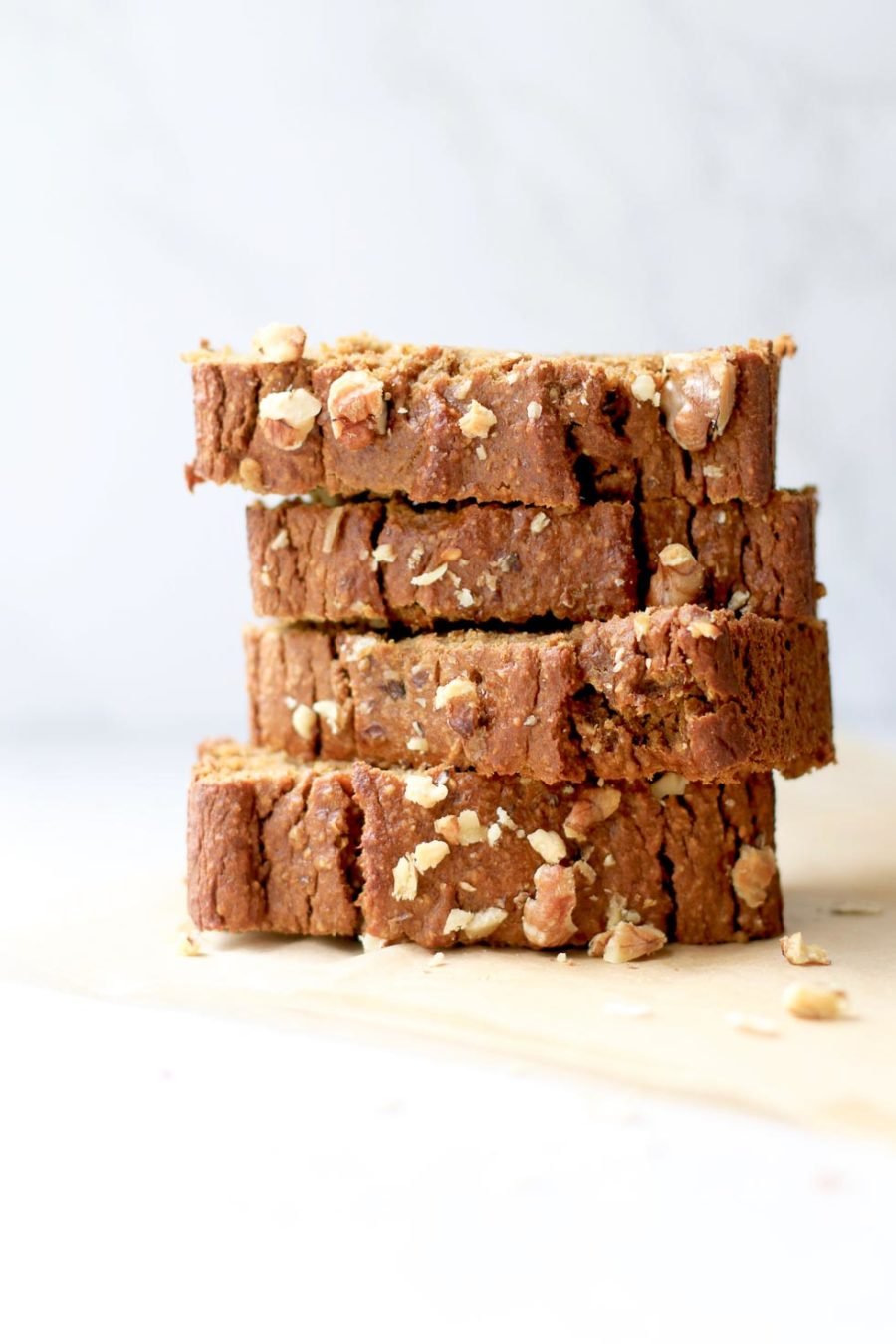 Pumpkin bread slices stacked up with walnuts scattered around them