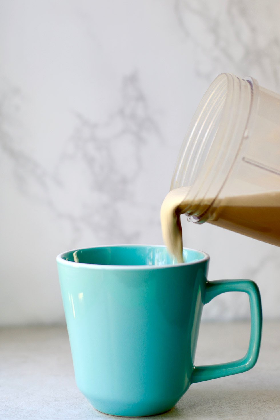 pouring cashew coffee into a blue mug