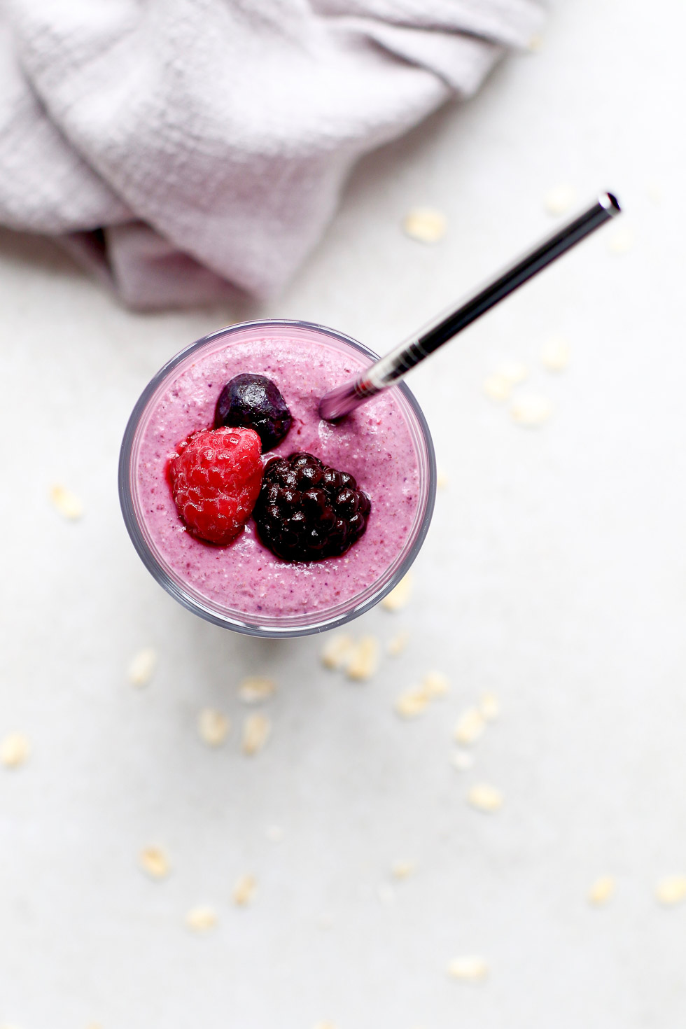 Triple Berry Hemp Smoothie with berries on top and oats around.