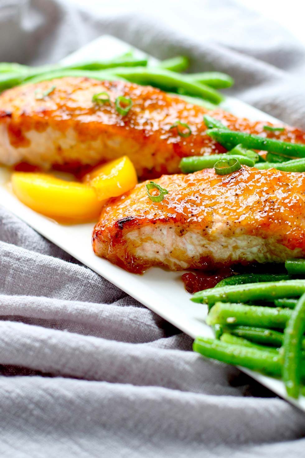 Salmon on a white plate surrounded by green beans