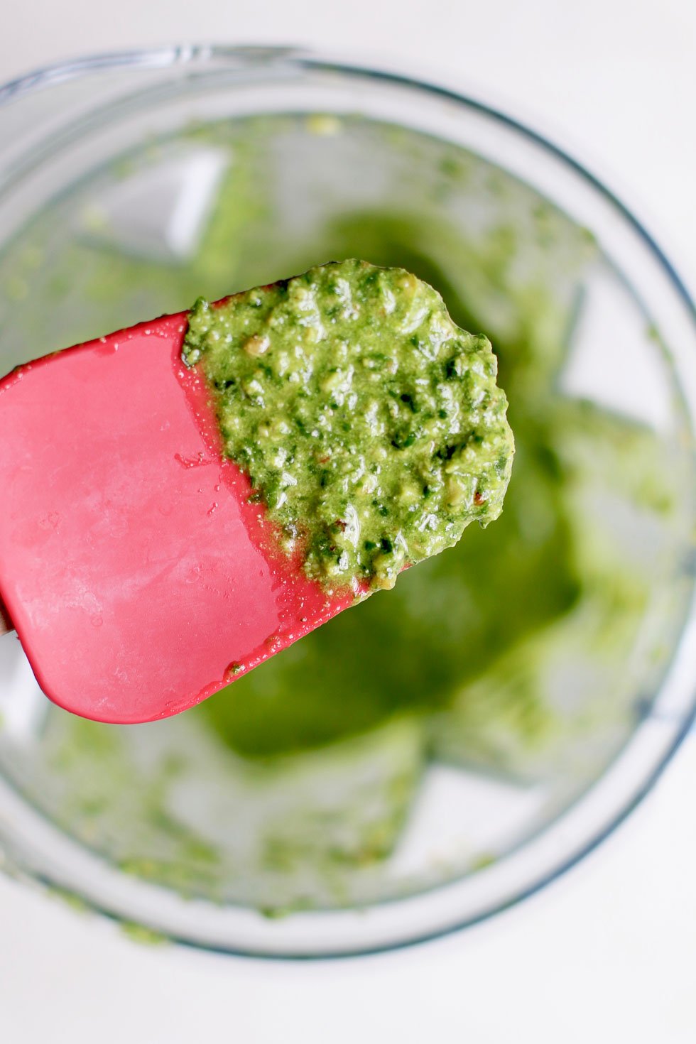 Close up of walnut pesto on a spatula and blender