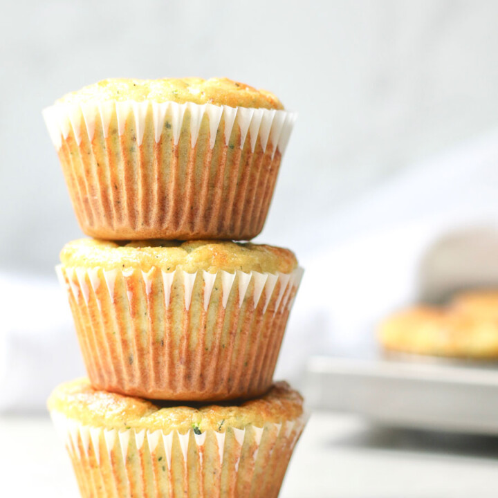 3 zucchini Muffins stacked with muffin tin in background