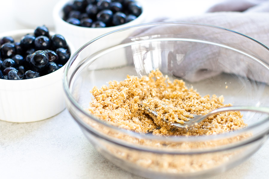 Healthy Blueberry Crisp - Oat Walnut Topping in bowl with blueberries in background