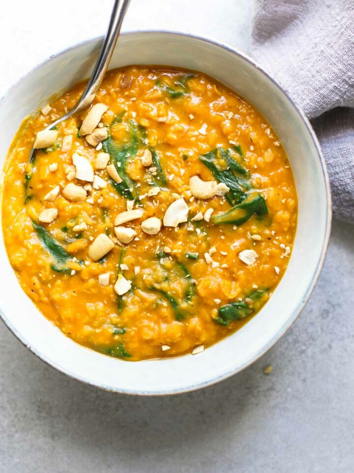 Pumpkin Lentil Curry in a bowl with cashews in a gray bowl with gray napkin