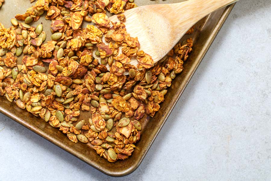 pan of fresh homemade granola with a wooden spatula