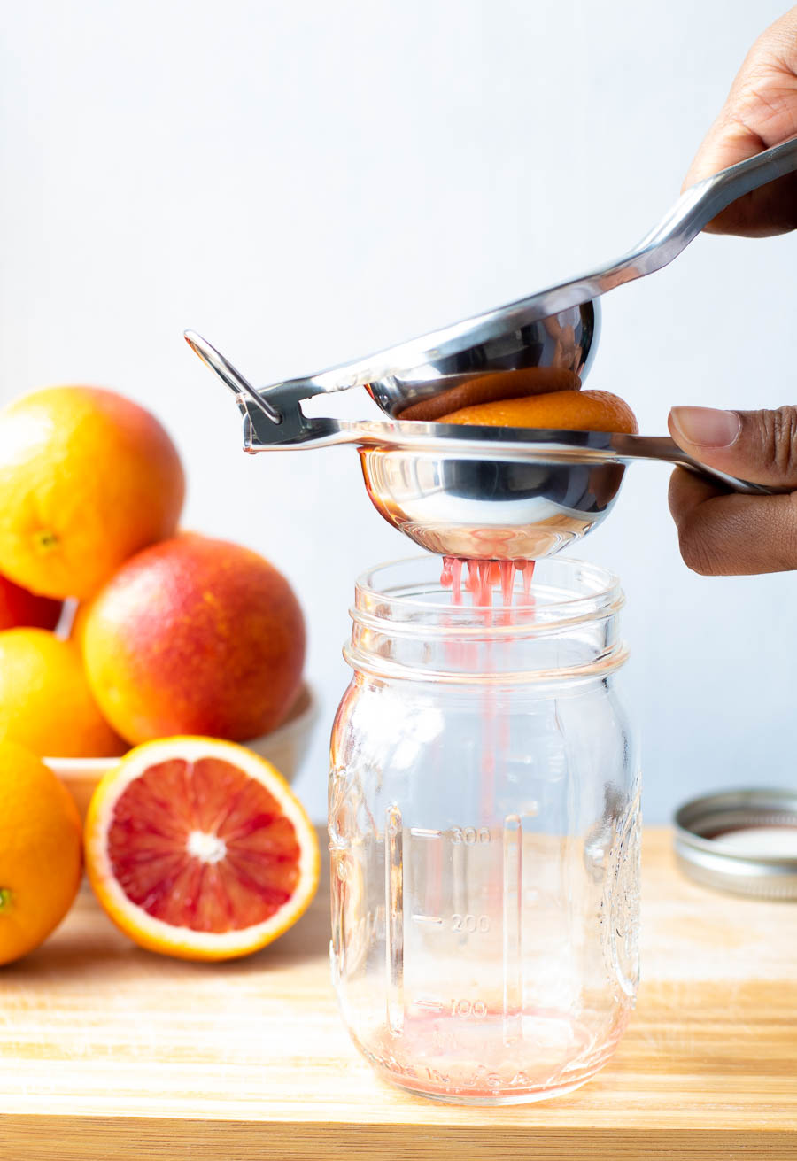 Squeezing blood orange juice into a jar