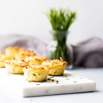 Cheddar Cauliflower Bites on Marble with Chives in Background