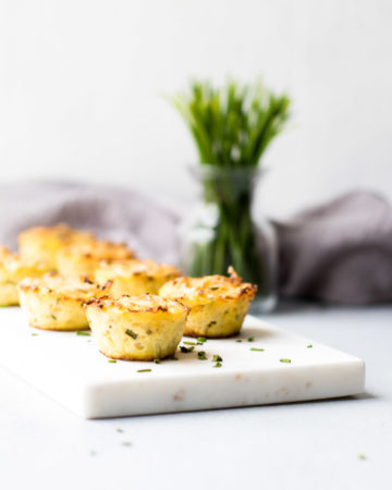 Cheddar Cauliflower Bites on Marble with Chives in Background