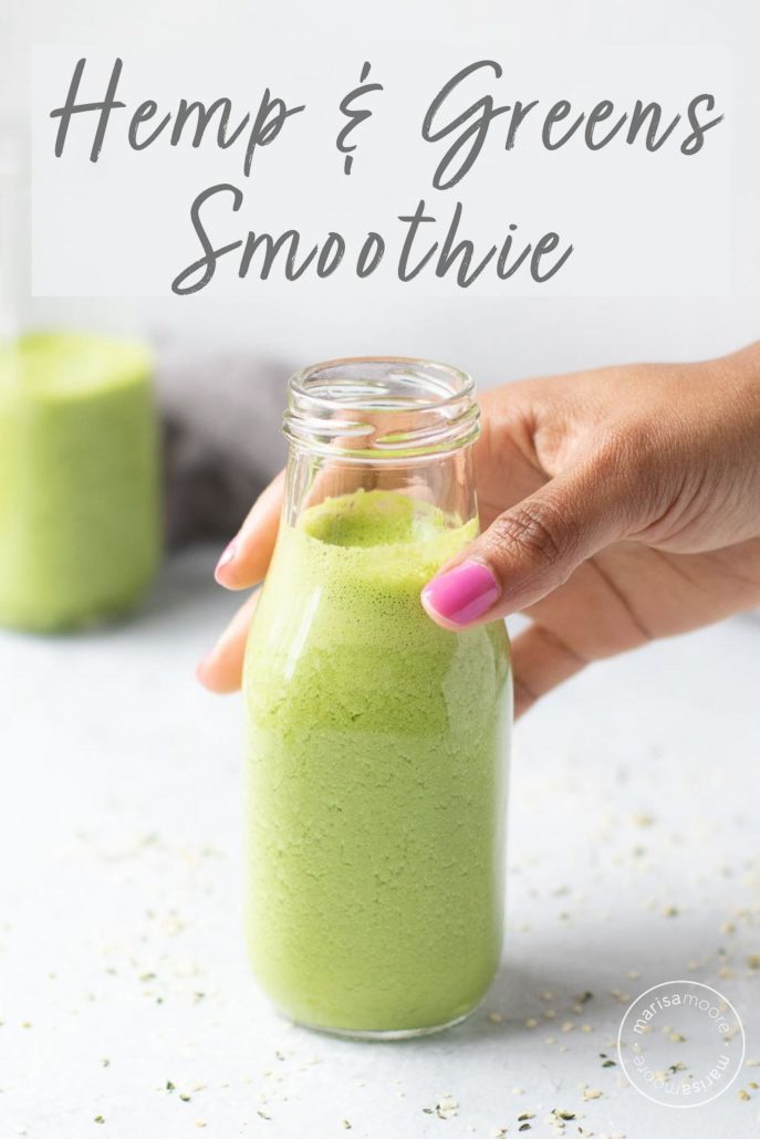 Green smoothie with hemp seeds and a hand grabbing the bottle