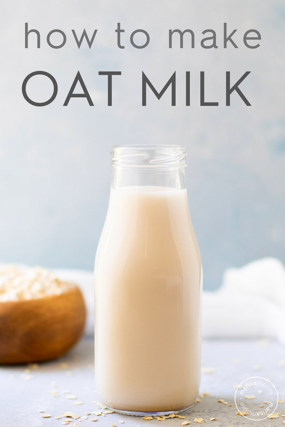oat milk in a bottle with dry oats scattered around