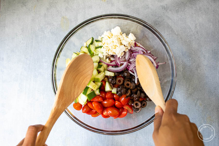 Making Mediterranean Pasta Salad in Bowl with two spoons