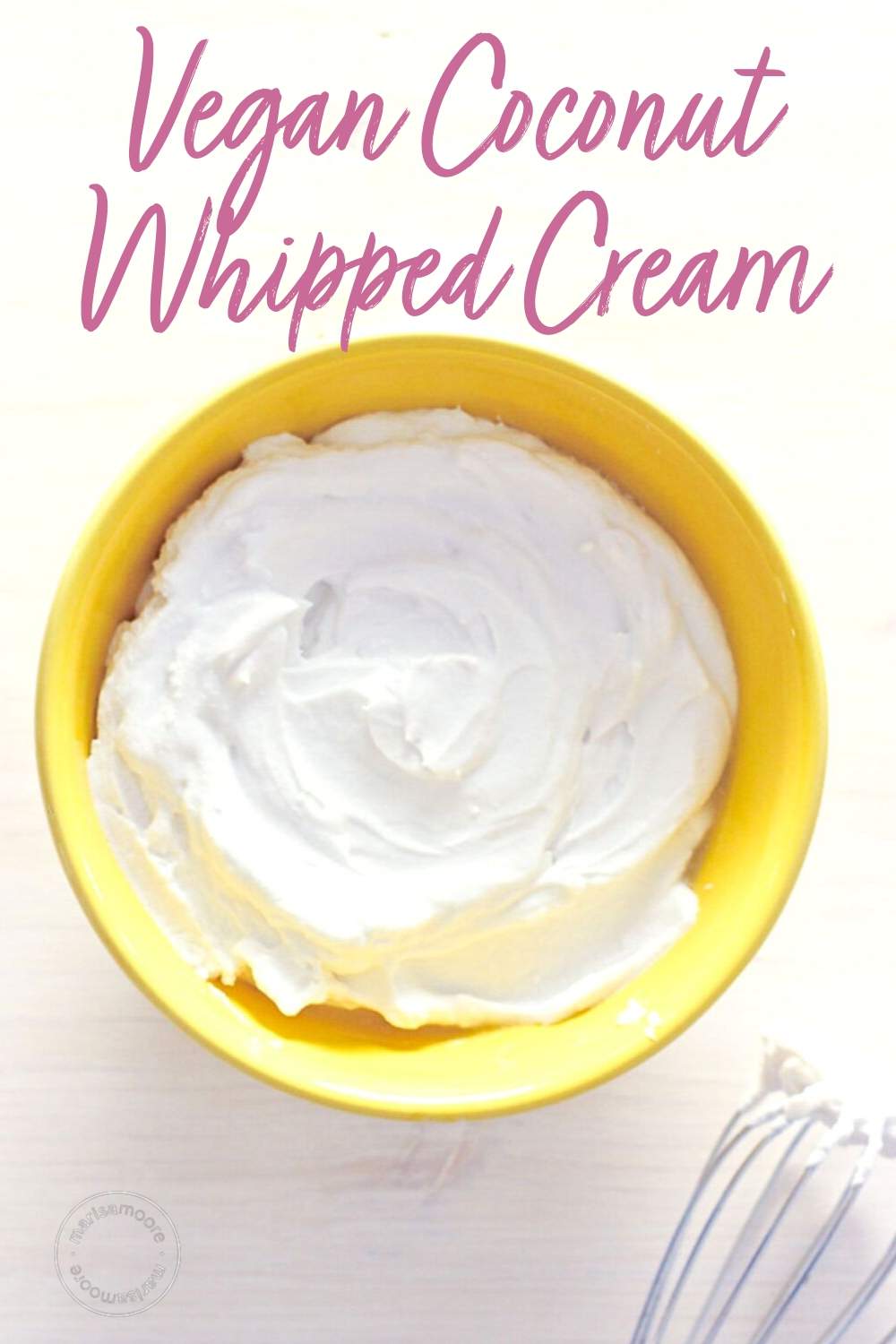 Yellow bowl with whipped coconut cream and a whisk on the side
