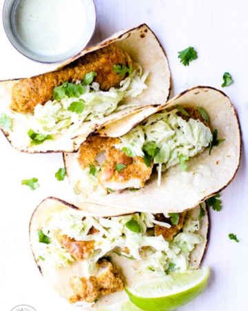 Fish tacos with a jar of cilantro spilling out