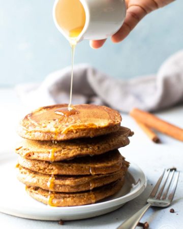 stacked gingerbread pancakes with syrup being poured