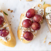 Roasted Grape Goat Cheese Toasts on a white cheese board