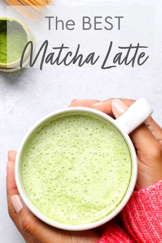 matcha latte in a mug with hands holding it