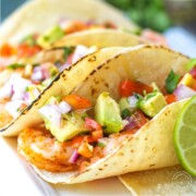 two avocado and shrimp tacos on a plate