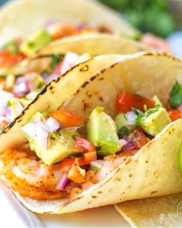 two avocado and shrimp tacos on a plate