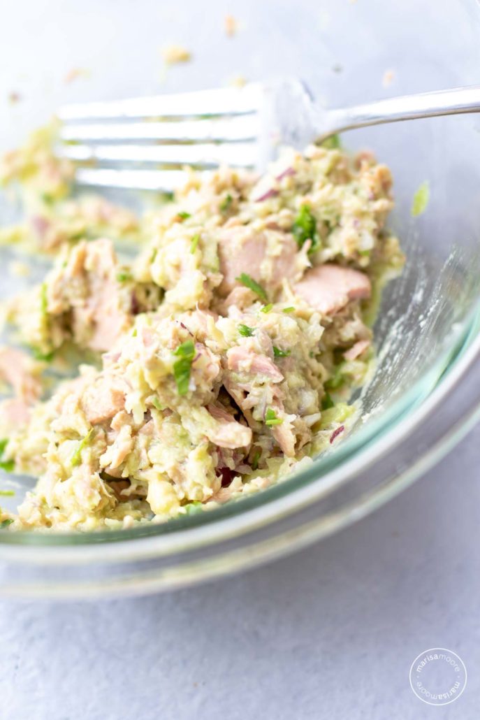 avocado lime tuna salad in clear mixing bowl with a fork