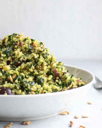 Superfood salad piled high in white bowl with sunflower seeds scattered around