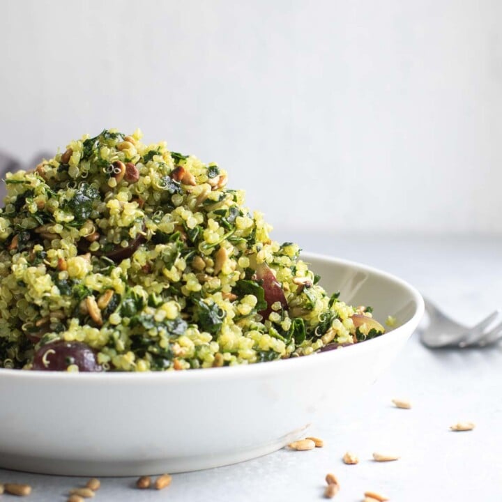 Superfood salad piled high in white bowl with sunflower seeds scattered around