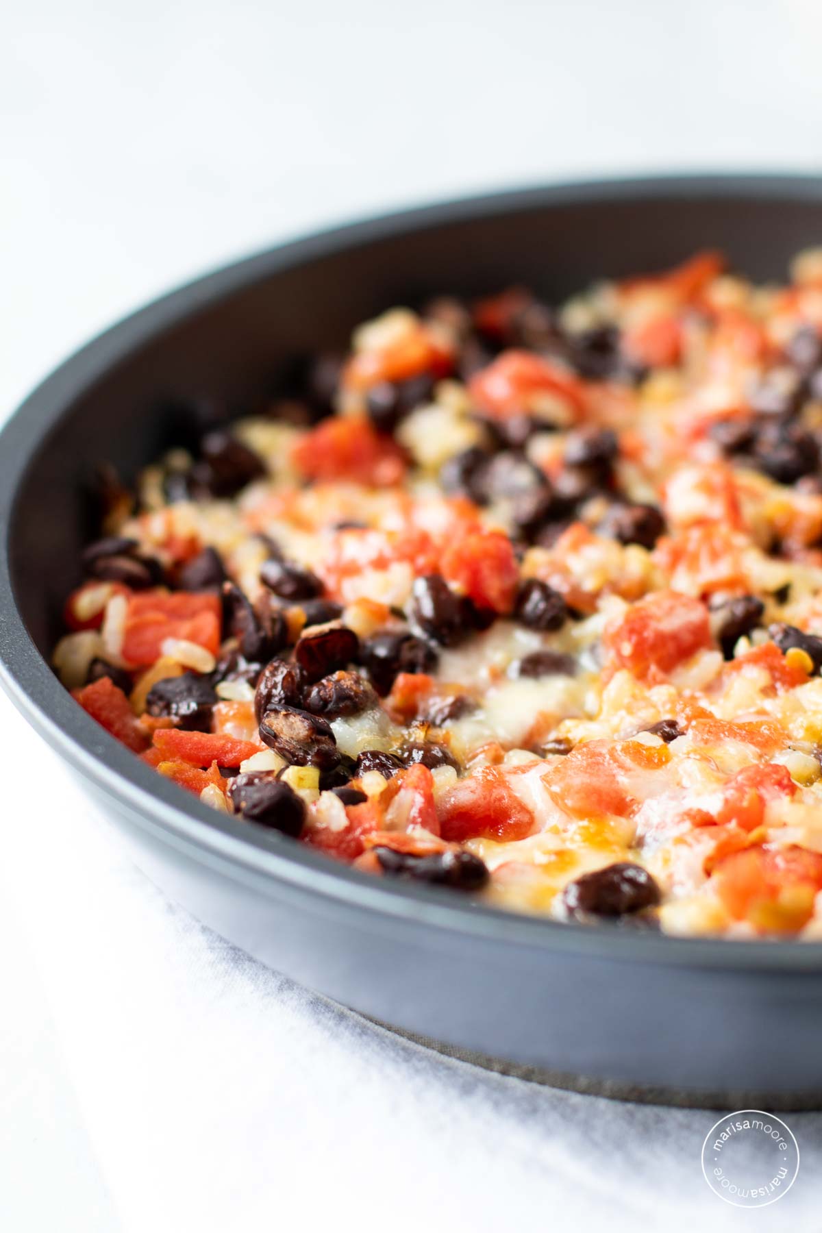 Skillet with black beans, tomatoes, rice and melted cheese