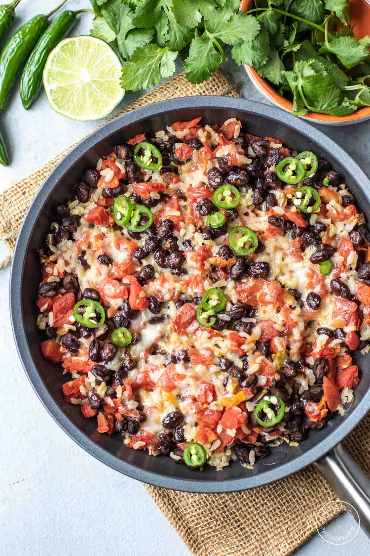 black bean skillet with limes, cilantro and peppers around it