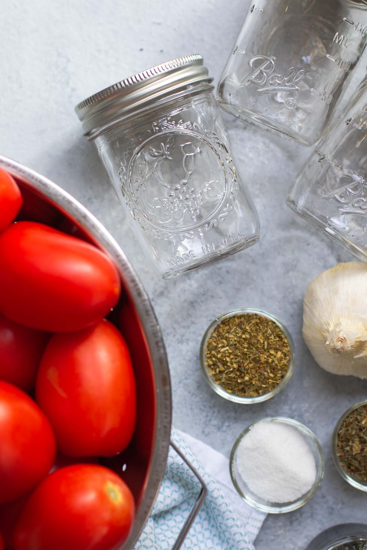 Ingredients in a flatlay - tomatoes, herbs, sugar and half pint jars