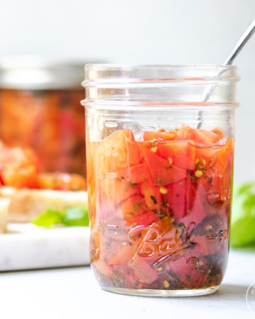 Jar of tomatoes with bruschetta in the background