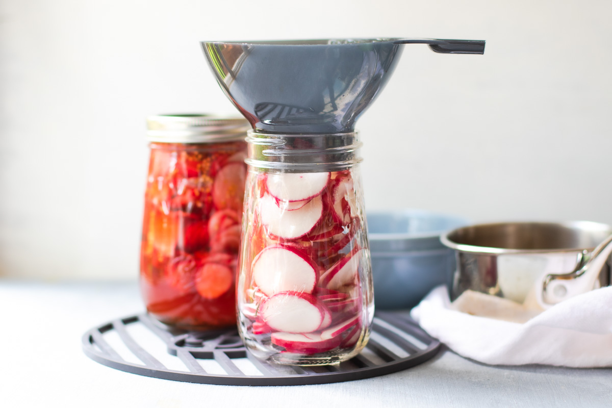 two flute jars filled radishes  - one with a funnel on top