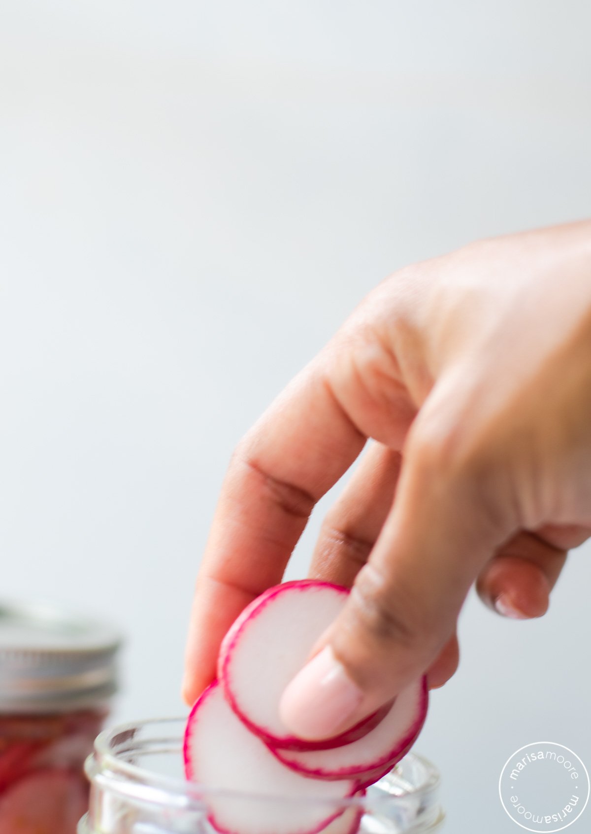 Radish slices being added to a jar