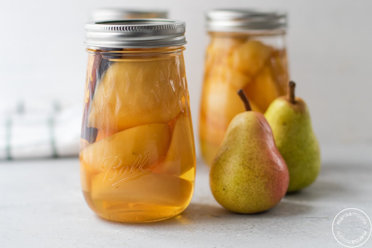 2 jars of canned pears with 2 fresh pears on the side