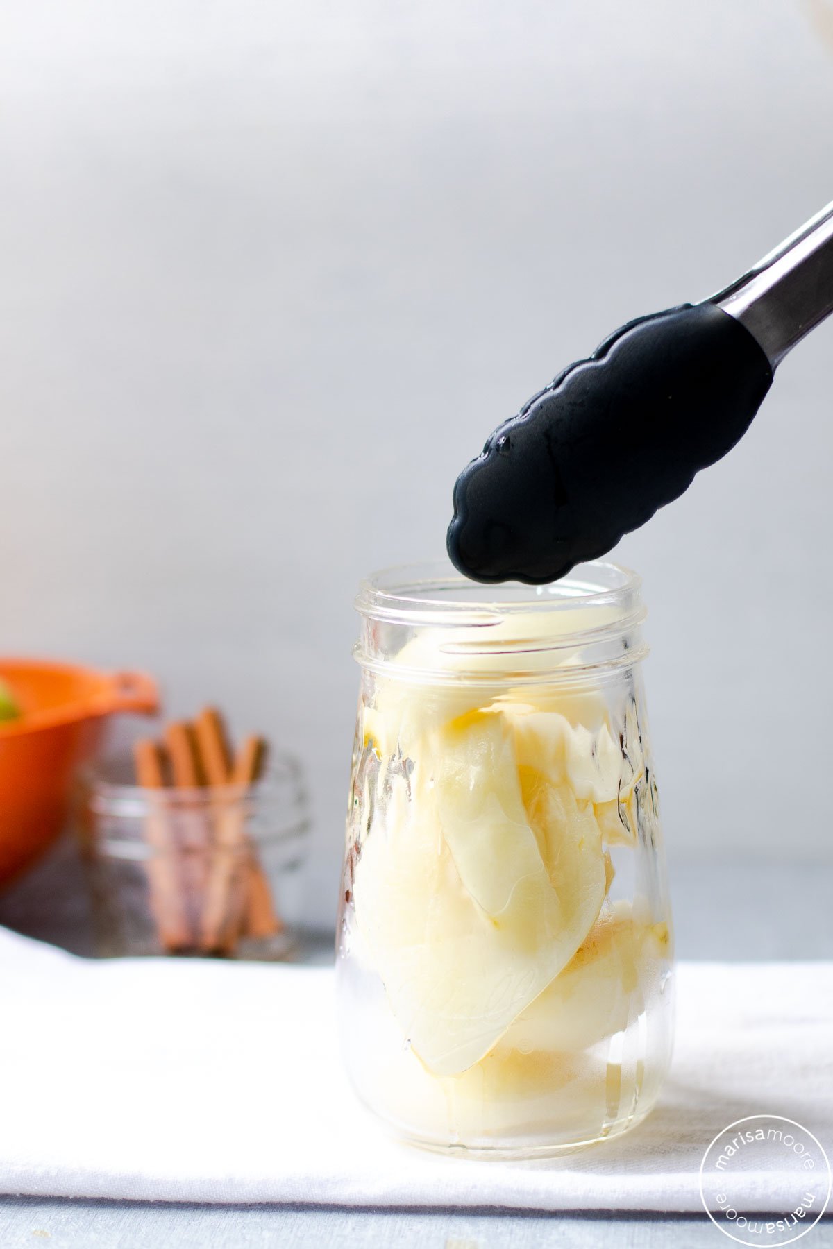 tongs adding hot pears to the hot jar