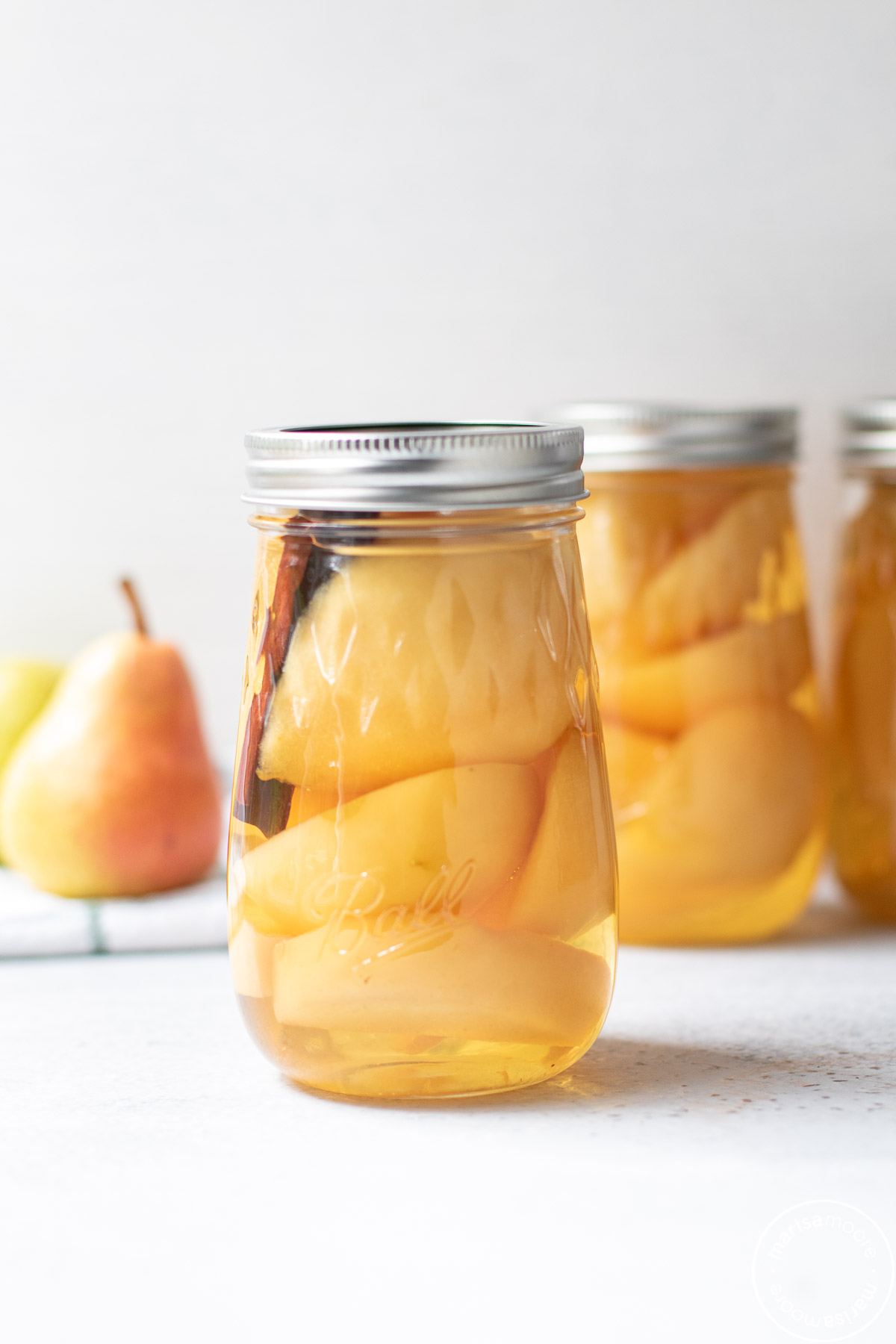 pears in flute shaped jars with a fresh pear in background