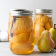 3 jars of canned pears with 2 fresh pears on the side