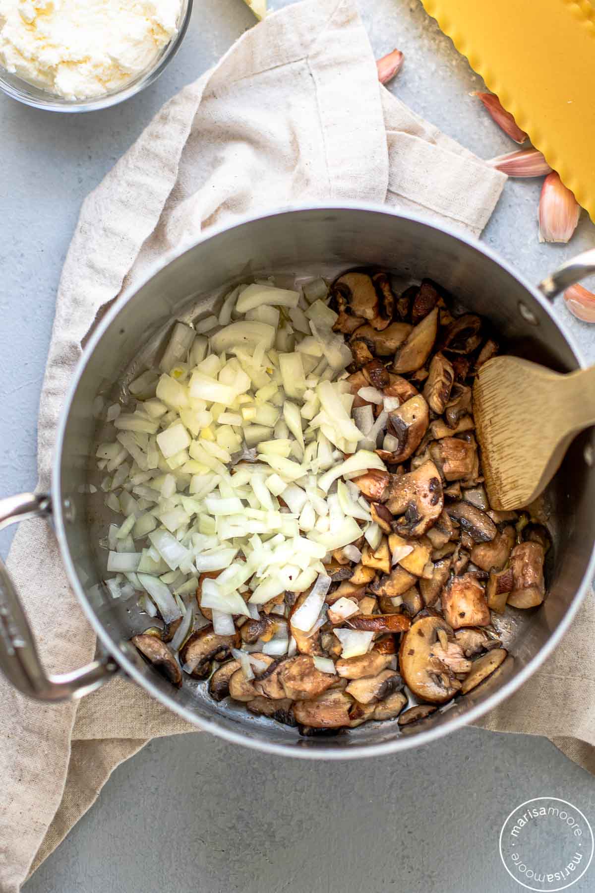 Pot of cooked mushrooms and raw onions added in