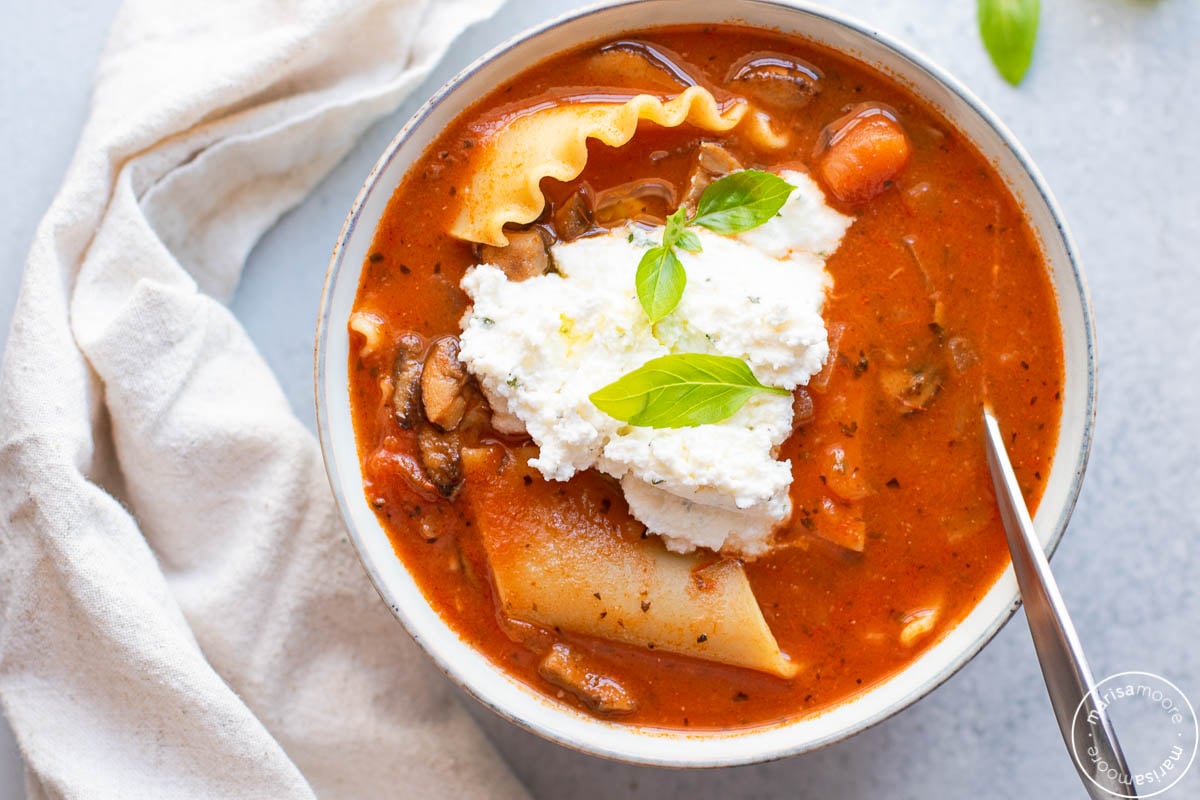 Bowl of lasagna soup with a spoon and napkin on the side