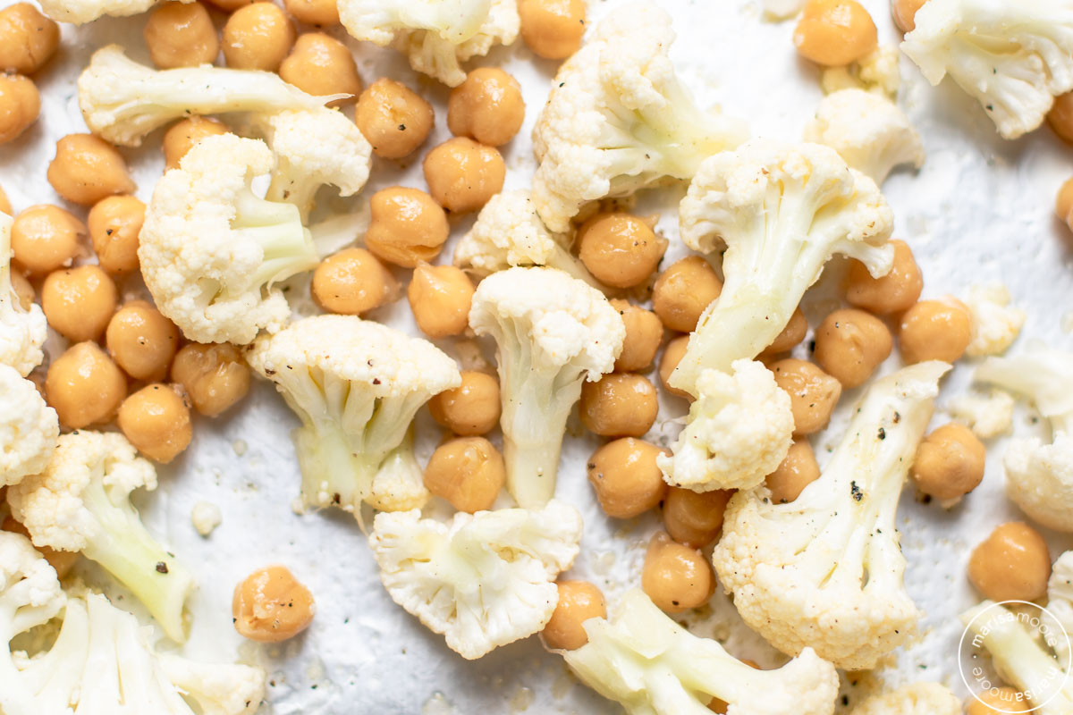 raw cauliflower and canned chickpeas on a sheet pan close up
