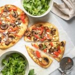 sliced flatbread with bowls of arugula