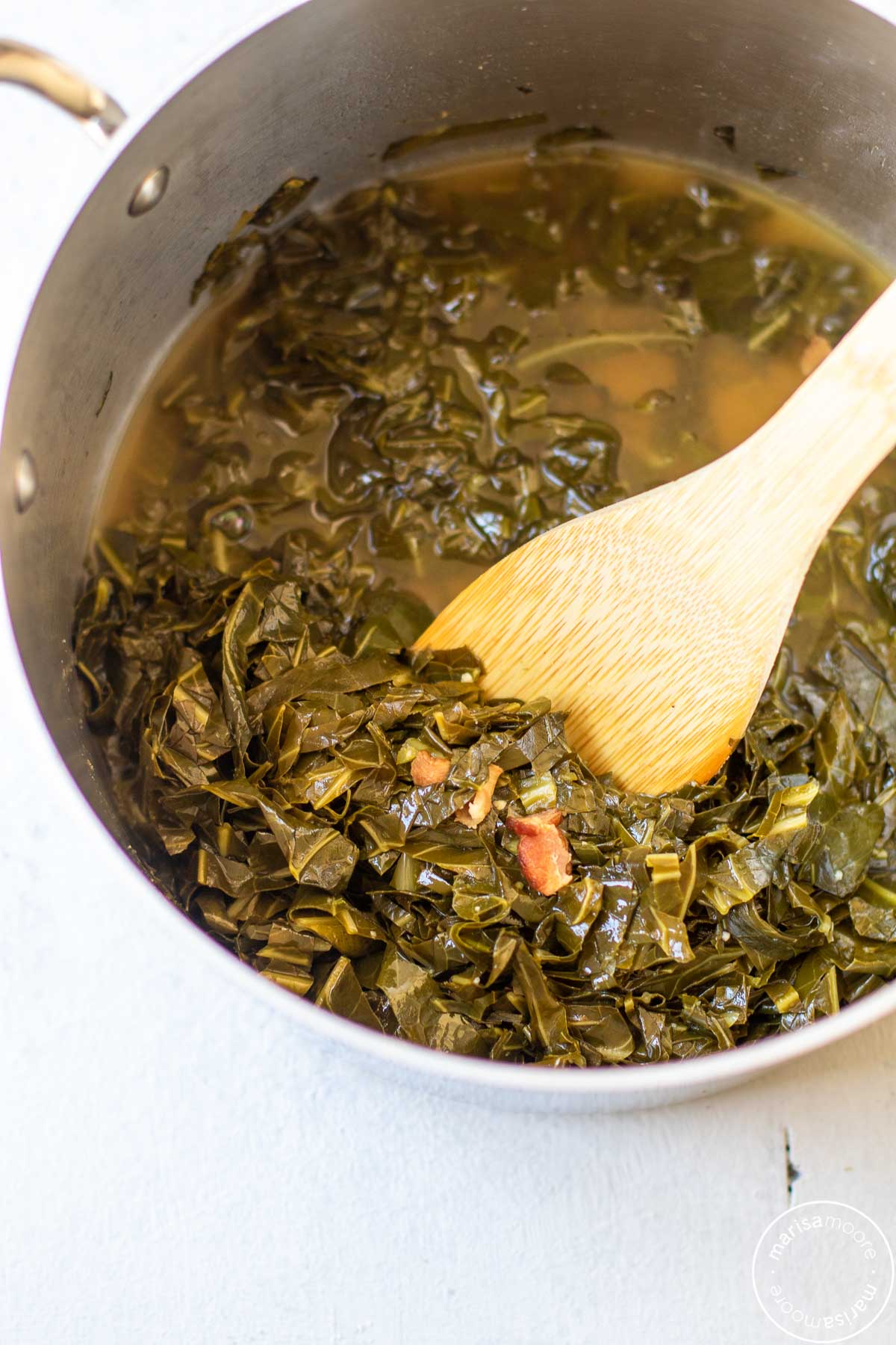 braised collard greens in a pot with a wooden spoon