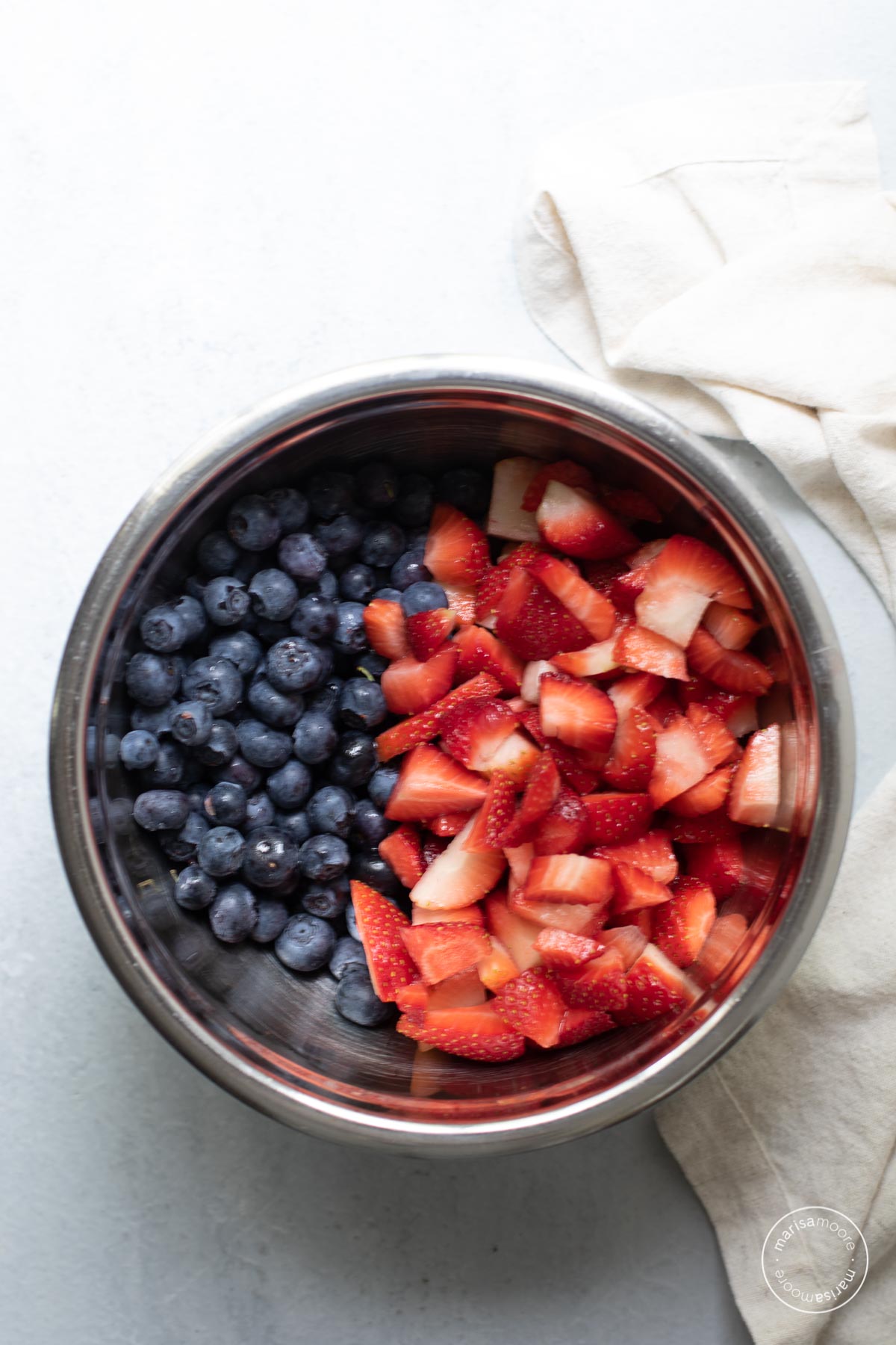 Chopped strawberries and whole blueberries in a stainless steel mixing bowl