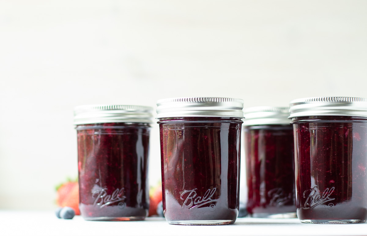 4 half pint jars of mixed berry jam side by side