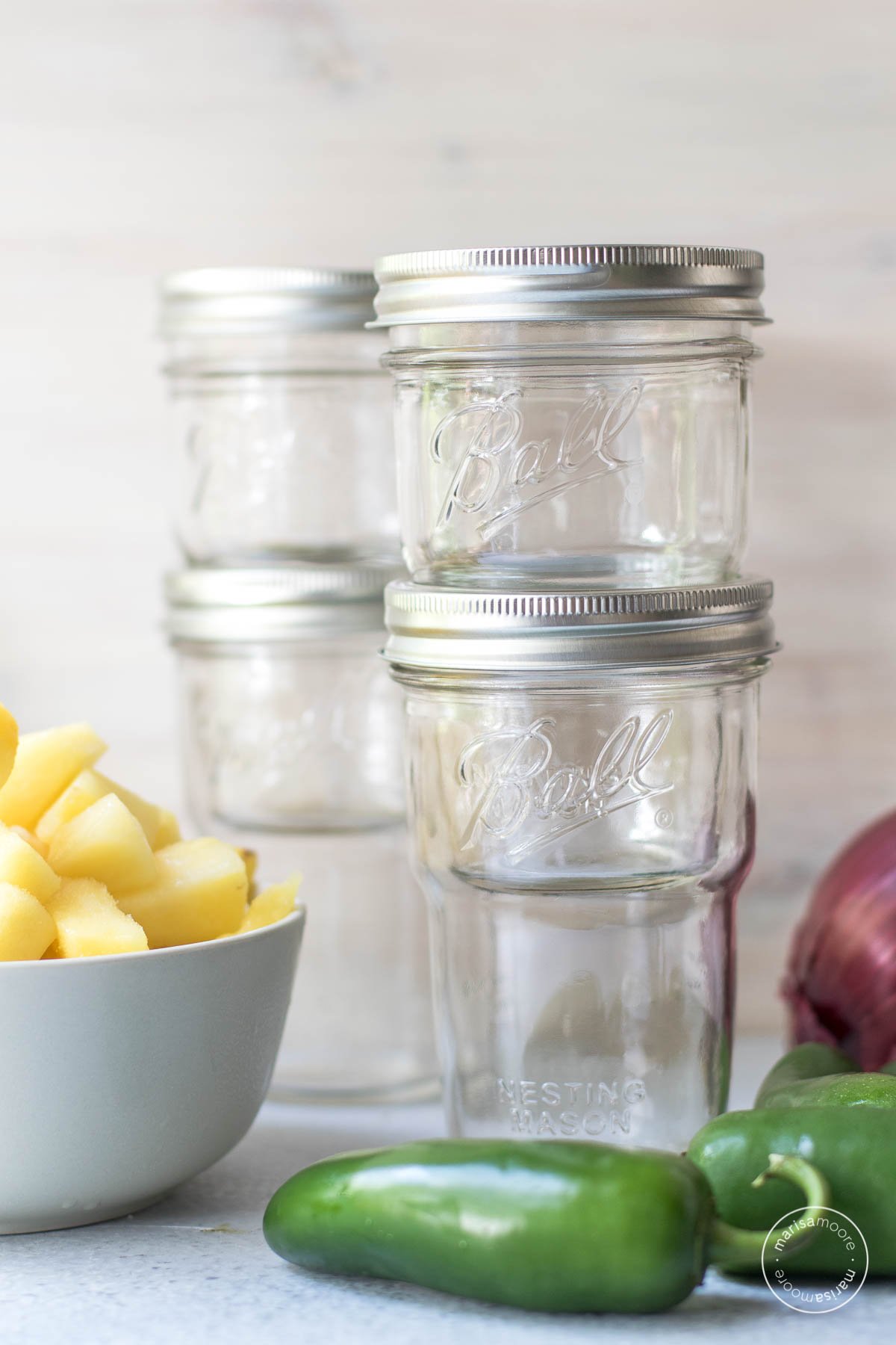 Ball nesting mason jars with a bowl of pineapple, jalapeno and red onion