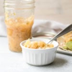 Pineapple relish in a white ramekin, jar of relish in background with tacos