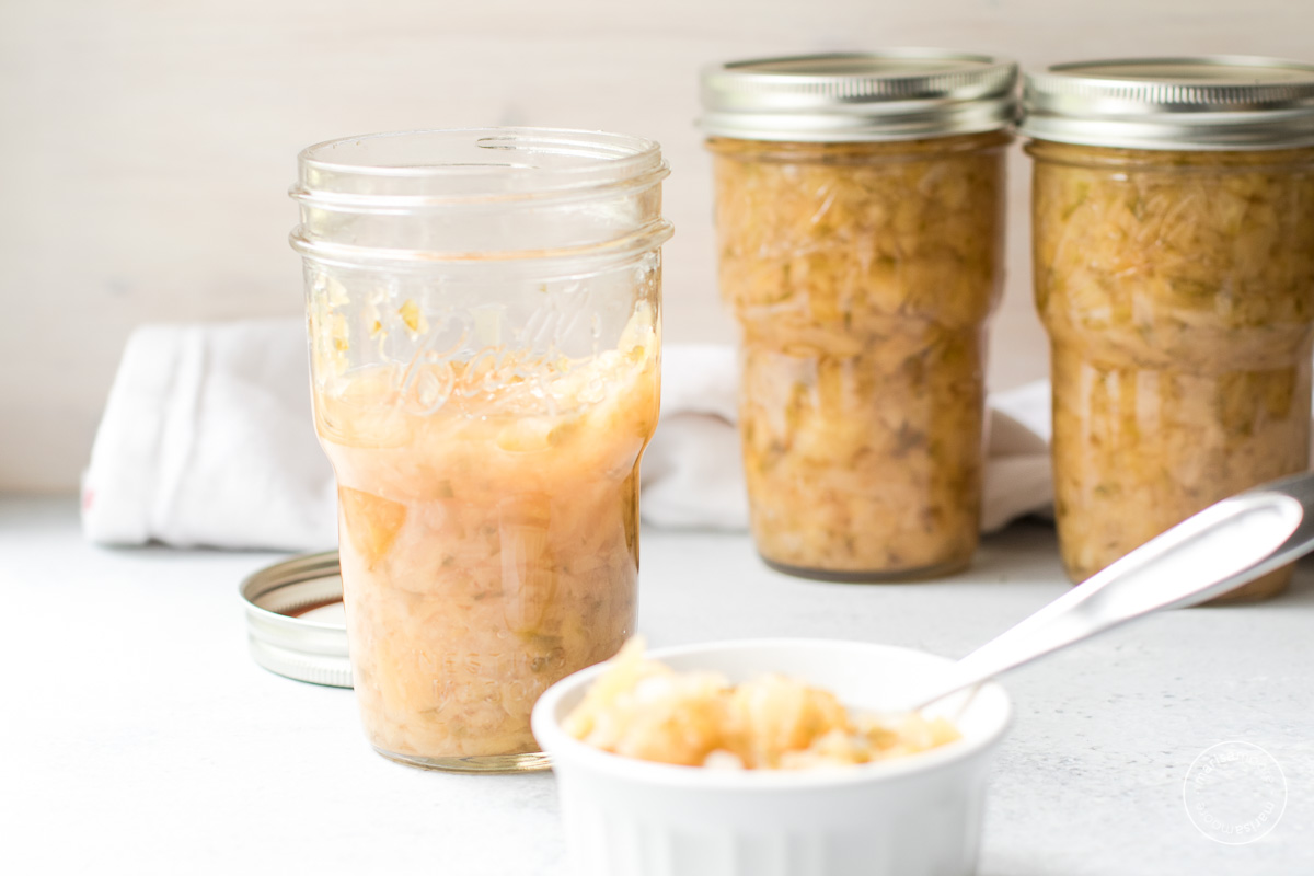 jars of pineapple relish with some relish in a white ramekin